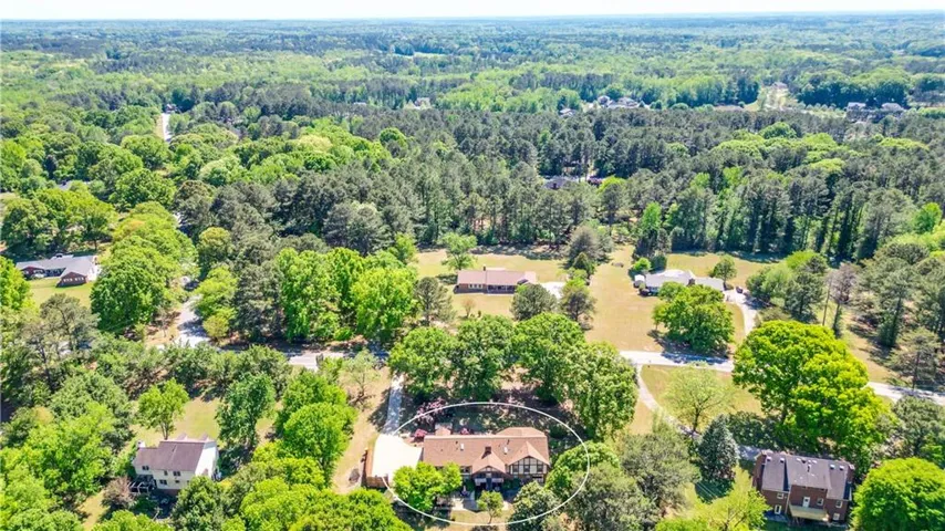 Aerial view of the property, showcasing its traditional architectural style with a gabled roof, surrounded by mature trees and a verdant landscape