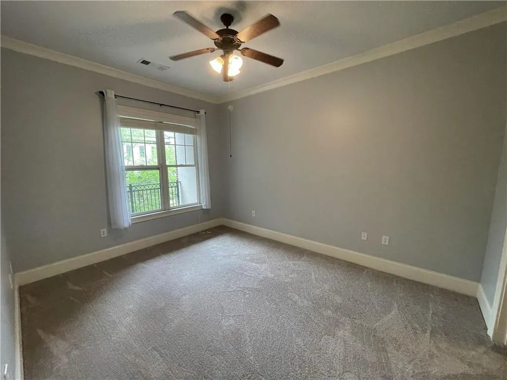 Carpeted spare room featuring crown molding and ceiling fan