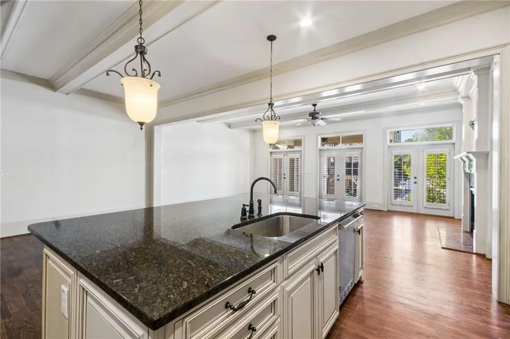 Central kitchen island with dark speckled countertop, undermount sink, and integrated dishwasher