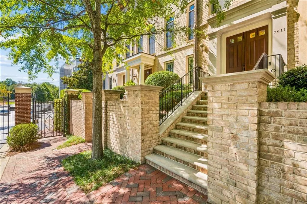 Brick exterior with wrought iron railings and a double wooden entry door