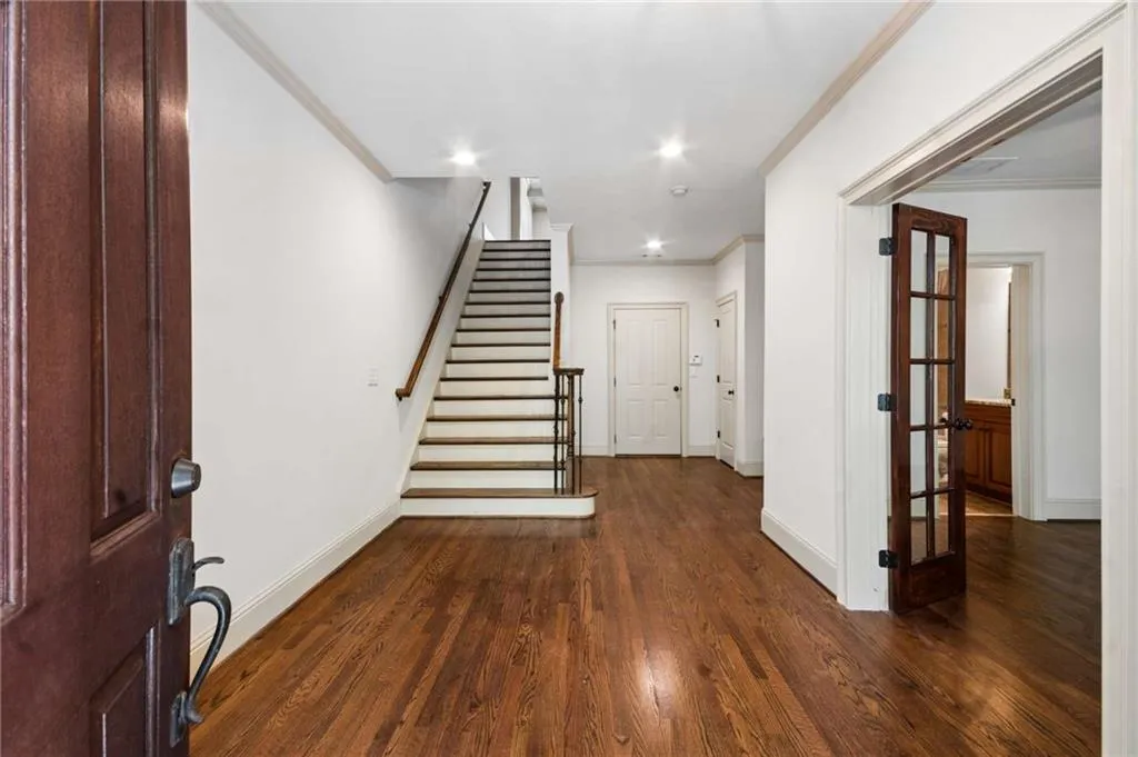 Hardwood flooring, recessed lighting, and a prominent staircase with wood banister