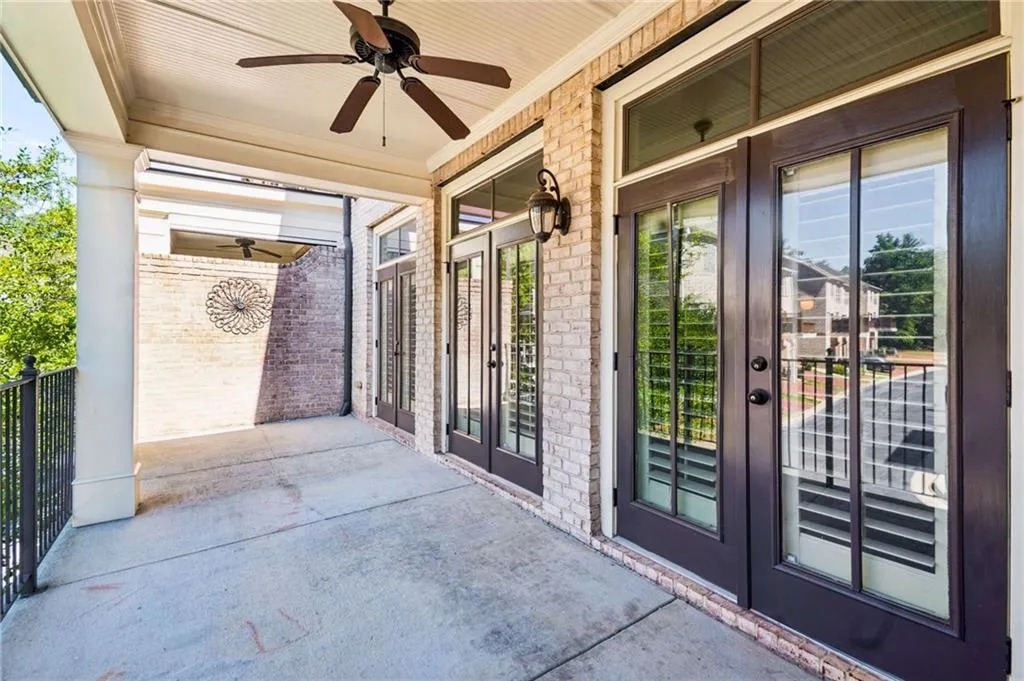 Covered porch featuring a beadboard ceiling, ceiling fan, brick exterior, and multiple sets of French doors with transom windows