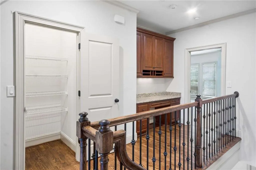 Hardwood flooring, built-in desk with overhead cabinetry, light-colored countertop, recessed lighting, and a closet with wire shelving