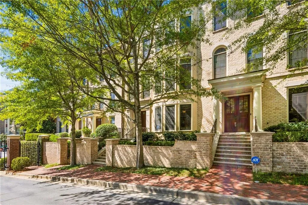 Brick facade with arched windows, double entry doors, columned portico, and mature landscaping