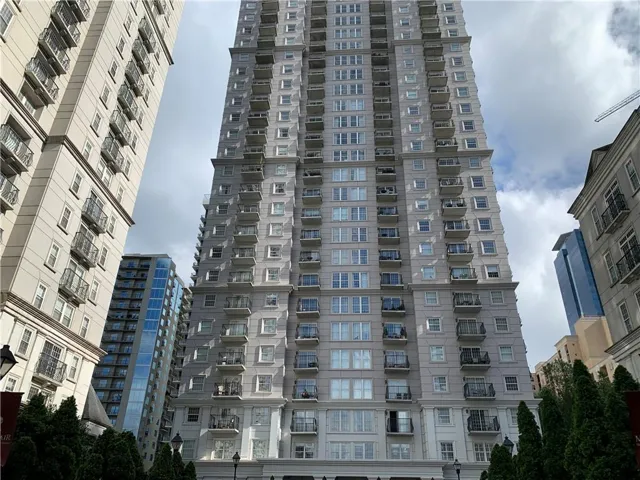 High-rise building with multiple balconies, a light-toned facade, and numerous windows