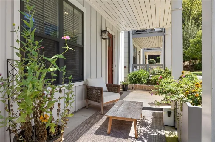 Covered front porch with vertical board siding and a red entry door