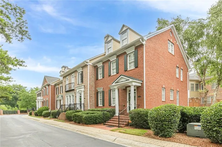 Brick exterior with white trim, dormer windows, and a covered portico entry