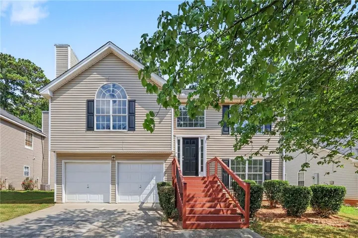 Two-car garage, arched window, exterior siding, red painted entry stairs, black front door