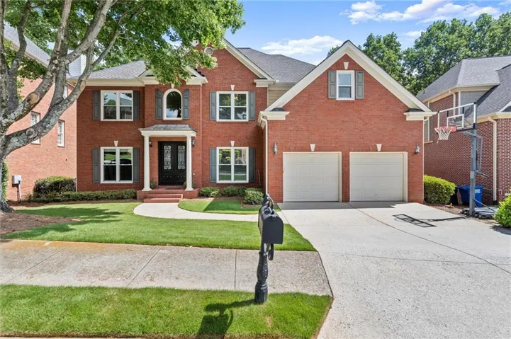 Brick exterior with decorative shutters, covered entry with double doors, two-car garage, and concrete driveway