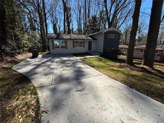 Tri-level home with board and batten siding, concrete driveway, and a front lawn