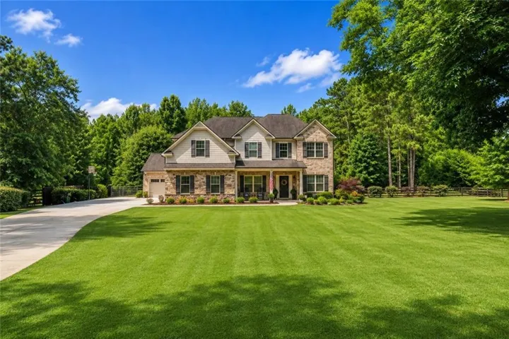 Stately two-story residence featuring a stone and siding facade, a two-car garage, and a covered front porch