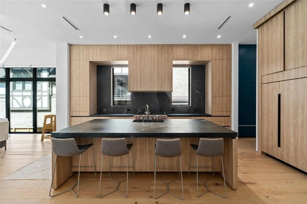 Designed for both beauty and functionality, this gourmet kitchen features custom white oak cabinetry with mitered, leathered countertops, an oversized island, and premium Wolf appliances. It seamlessly opens to the dining area and great room, making it perfect for both entertaining and everyday living.