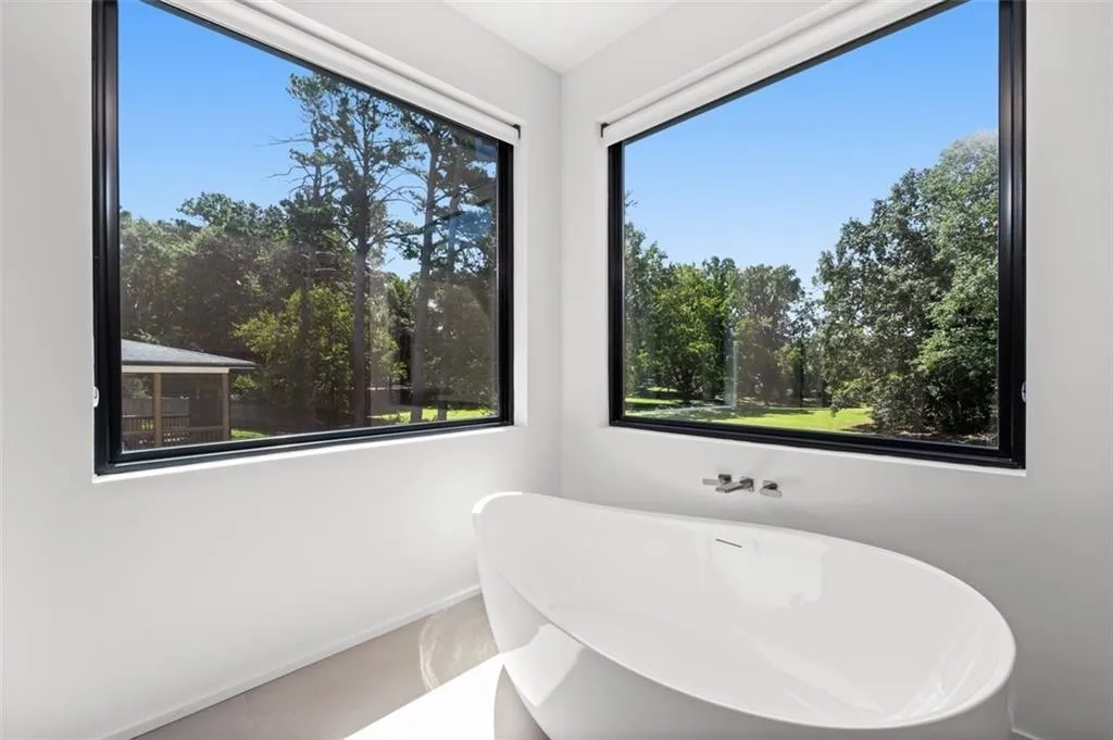 Luxuriously appointed, this spa-like retreat features an oversized custom vanity with lighted mirrors, a seamless oversized shower, a soaking tub, and two picture windows that fill the space with natural light.