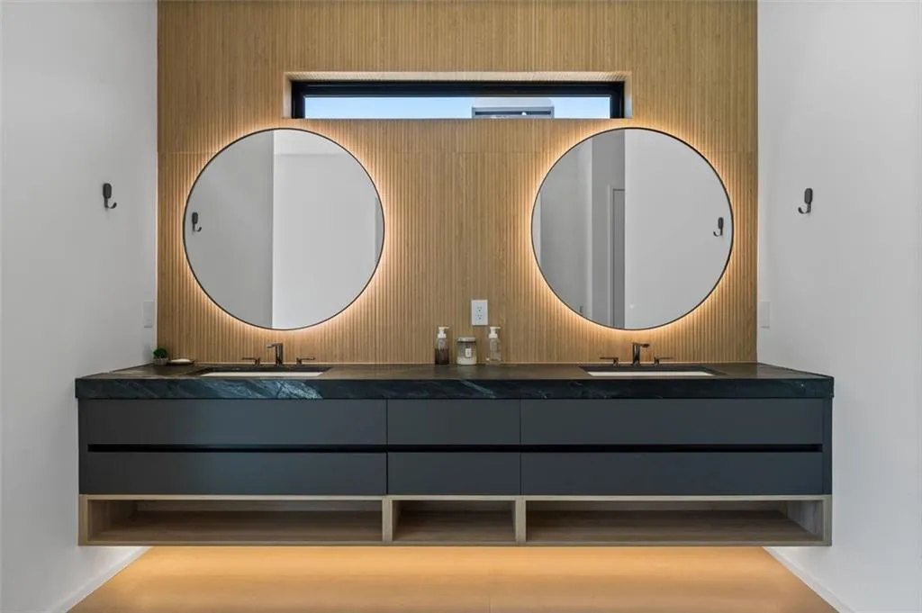Luxuriously appointed, this spa-like retreat features an oversized custom vanity with lighted mirrors, a seamless oversized shower, a soaking tub, and two picture windows that fill the space with natural light.