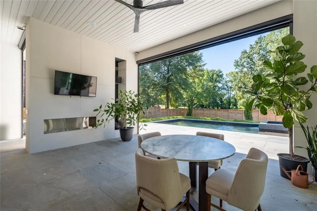 Overlooking the private, resort-style backyard, this inviting outdoor space is perfect for relaxation or entertaining. It features a modern linear fireplace, ceiling fan, and automated screens for comfort and convenience.