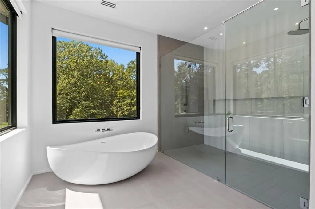Luxuriously appointed, this spa-like retreat features an oversized custom vanity with lighted mirrors, a seamless oversized shower, a soaking tub, and two picture windows that fill the space with natural light.