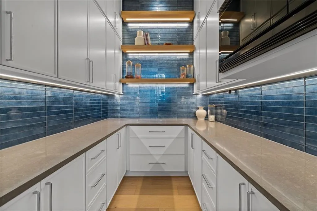 Equipped with custom cabinetry and countertops, 12-foot ceilings, custom shelving, a built-in microwave, and a stunning backsplash, this space sits directly off the kitchen-perfect for effortless entertaining and added functionality.