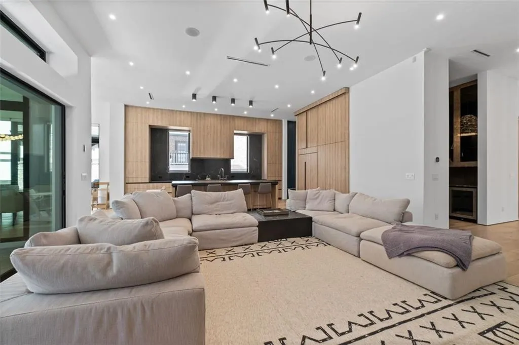 Located just off the kitchen, this inviting space features 12-foot ceilings, white oak floors, a sleek modern linear fireplace, striking Moooi lighting, and built-in drawers. Oversized sliding glass doors and expansive windows frame picturesque views of the resort-style backyard, seamlessly blending indoor and outdoor living.