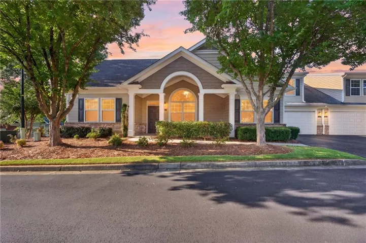 Covered entry with arched detailing, stone accents, and manicured landscaping