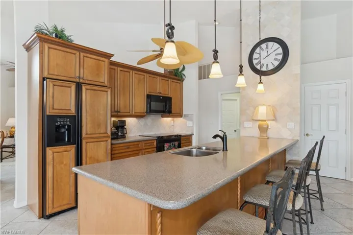 Kitchen featuring black appliances, sink, ceiling fan, tasteful backsplash, and decorative light fixtures