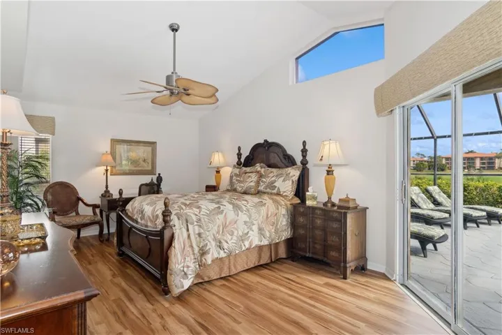 Bedroom with access to pool/lanai, wood-type flooring, vaulted ceiling, and ceiling fan