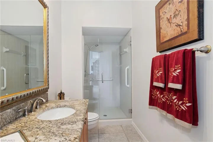 Bathroom featuring toilet, tile patterned flooring, vanity, and walk in shower