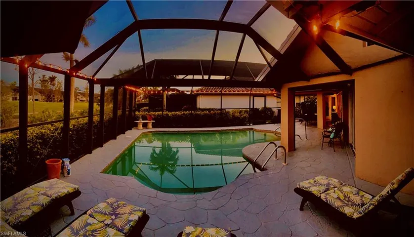 Pool at dusk featuring a lanai and a patio