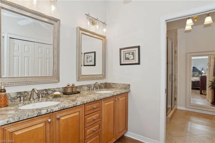 Bathroom featuring tile patterned floors, vanity, and an enclosed shower