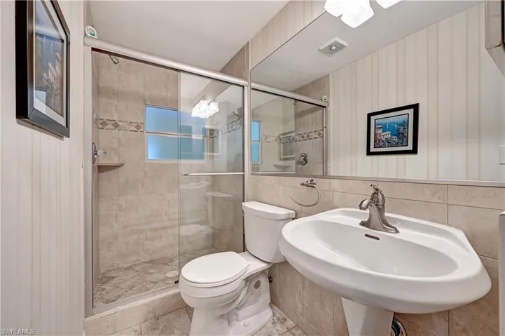 Bathroom featuring tile walls, tile floors, sink, and toilet