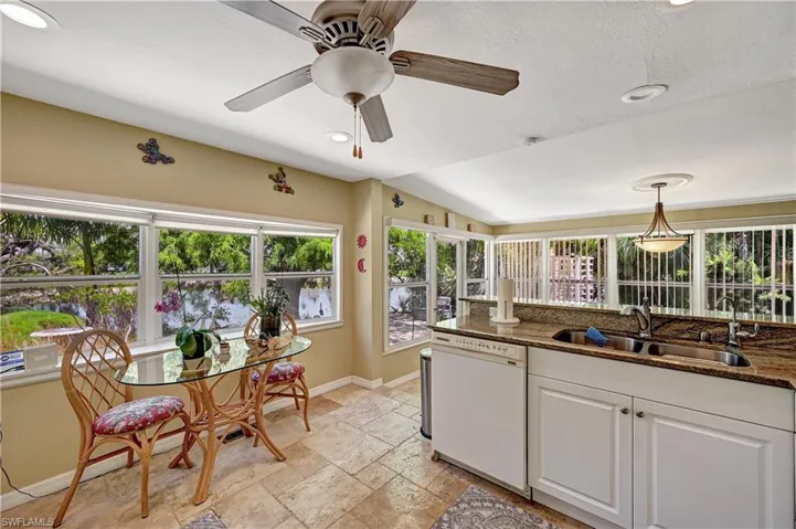 Kitchen with ceiling fan, light tile flooring, pendant lighting, white dishwasher, and white cabinetry
