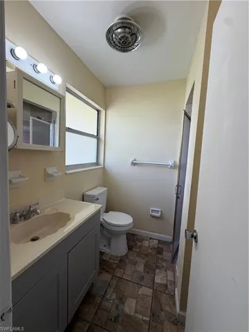 Master Bathroom featuring a vanity with an integrated sink, a wall-mounted mirror with overhead light fixture, a toilet, and patterned floor tiles