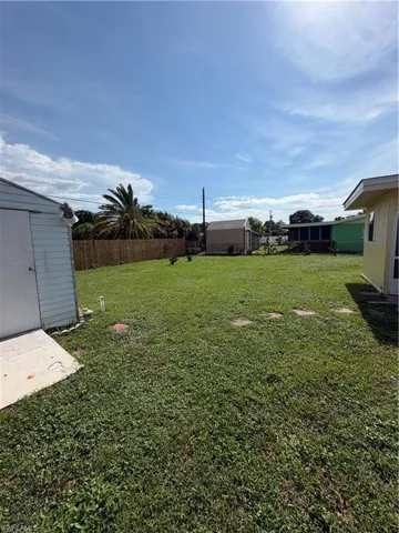 Spacious rear yard with a perimeter fence, mature palm tree, and a storage shed
