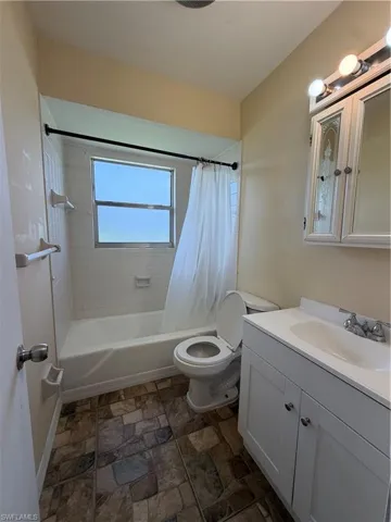 Guest Full bathroom featuring a white vanity with integrated sink, a white bathtub with subway tile surround, and patterned floor tiling