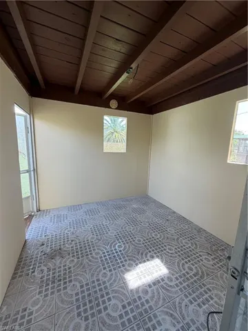 Interior space featuring exposed wood beam ceiling, patterned floor tiling, and neutral wall tones