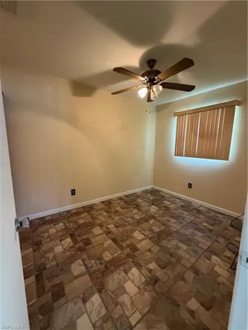 Room featuring patterned tile flooring, a ceiling fan with integrated lighting, a single window with horizontal blinds, and neutral wall paint