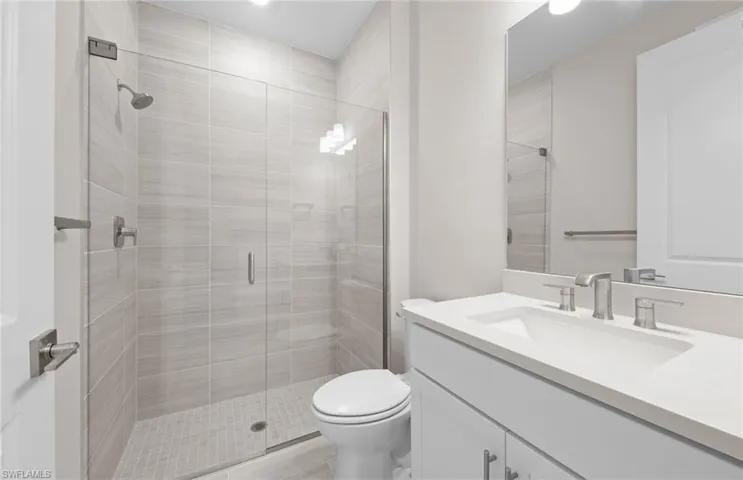 Bathroom featuring vanity, toilet, and a stall shower