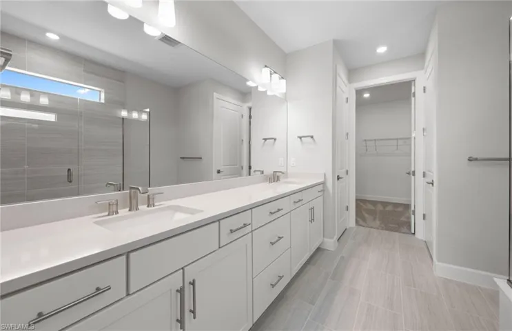 Full bathroom featuring double vanity, a shower stall, a walk in closet, recessed lighting