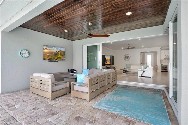 Living room featuring wood ceiling, ceiling fan, and brick floor