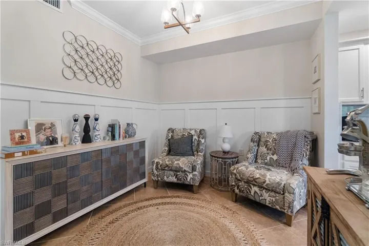 Living area with light tile patterned flooring, a chandelier, and crown molding