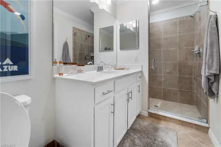 Bathroom with vanity, walk in shower, tile patterned flooring, and crown molding