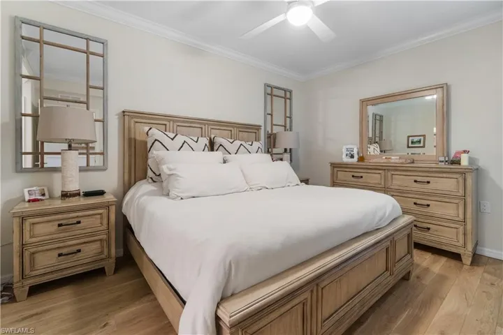 Bedroom with light hardwood / wood-style floors, crown molding, and ceiling fan