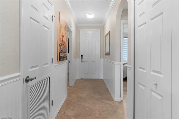 Corridor with light tile patterned floors and crown molding