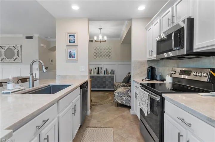 Kitchen featuring appliances with stainless steel finishes, sink, backsplash, light tile patterned floors, and white cabinetry
