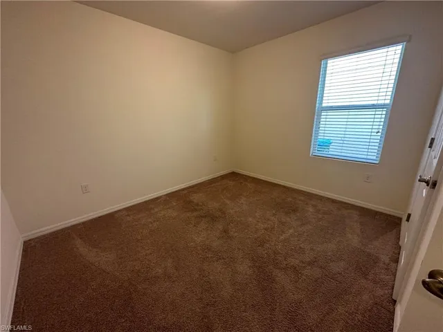 Spare room with dark carpet and baseboards