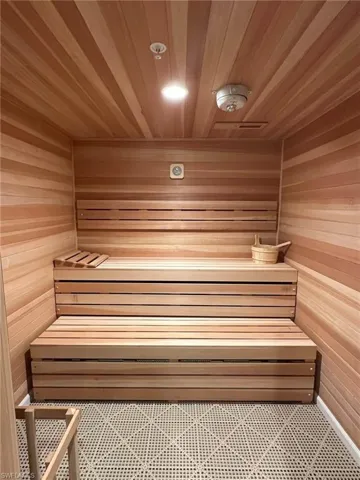 Wood-paneled sauna featuring tiered wooden benches and grid-patterned flooring