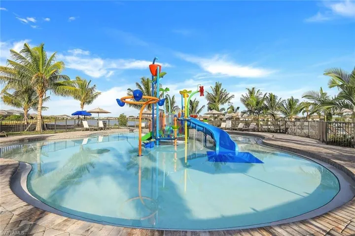 Zero-entry pool featuring a children's water play structure with a slide, water bucket, and spray features
