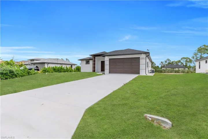 Prairie-style home featuring driveway, a front lawn, stucco siding, and a garage