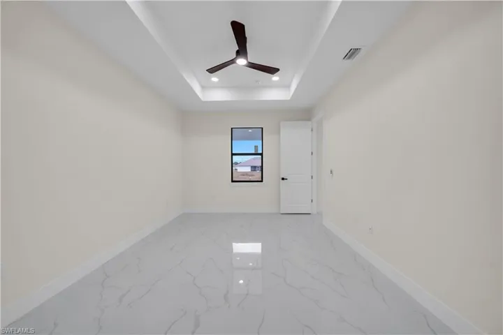 Spare room with recessed lighting, light marble finish flooring, a tray ceiling, and a ceiling fan