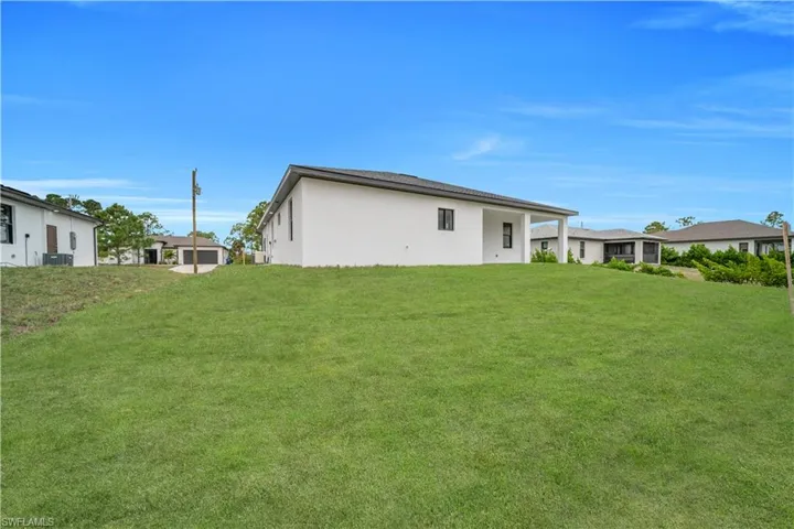 Rear view of house with a lawn and stucco siding
