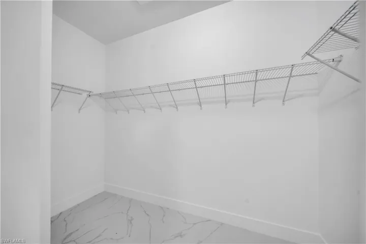 Walk in closet featuring light marble finish floors